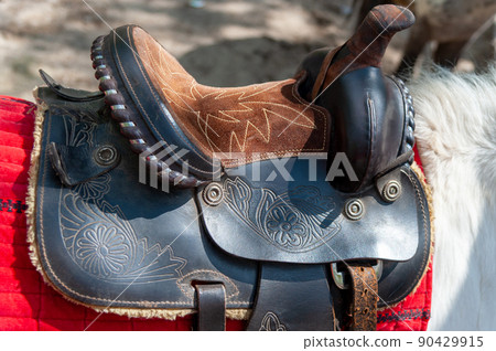Saddle with stirrups on a back of a horse Saddle with stirrups on a back of a horse 90429915