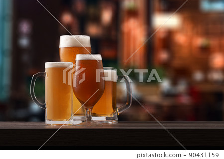 Four different glasses of beer on counter in pub. 90431159