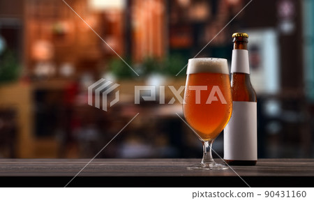 Bottle and glass of beer on counter in pub. 90431160