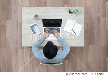 A bird's-eye view of a man typing on a laptop 90432080