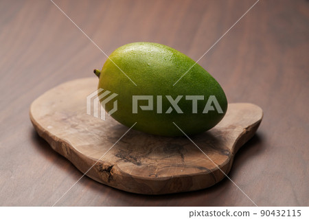 Ripe green mango washed and ready to eat on wood board Ripe green mango washed and ready to eat on wood board 90432115