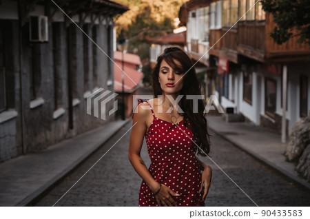 Beautiful sexy brunette girl in a red dress posing on street with paving stones in Italy Beautiful sexy brunette girl in a red dress posing on street with paving stones in Italy 90433583