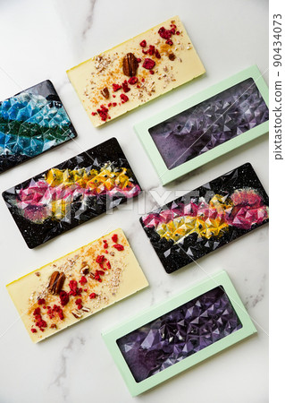 Hand-made bars of colorful chocolate on a light marble background 90434073