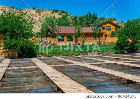 fish farm in a mountain valley with aquaculture cages and wooden buildings 90434375