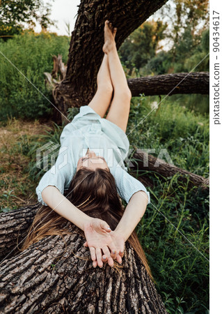 Nature and mental health. Barefoot woman in a dress is resting near the trees in nature Nature and mental health. Barefoot woman in a dress is resting near the trees in nature 90434617