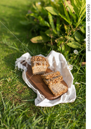 homemade grey bread with seeds on the wood board with the white cloth napkin on the green grass. High quality photo homemade grey bread with seeds on the wood board with the white cloth napkin on the green grass. High quality photo 90434690