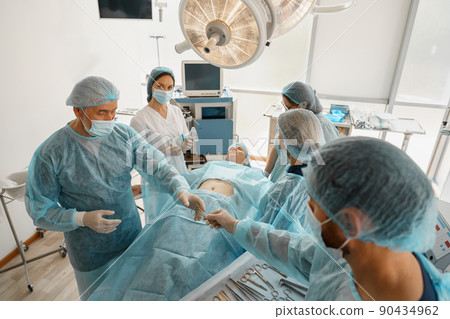Professional concentrated surgical team working with a patient in an operation room Professional concentrated surgical team working with a patient in an operation room 90434962