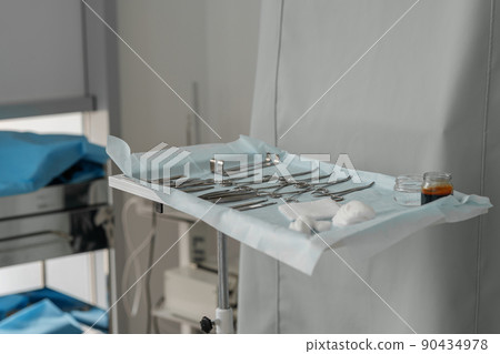 Surgical instruments and tools including scalpels forceps and tweezers arranged on table for surgery 90434978
