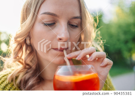 Beautiful European 30s girl having fun in cafe and drinking fruit cocktails with pleasure, outfit chilling in restaurant in weekend 90435381