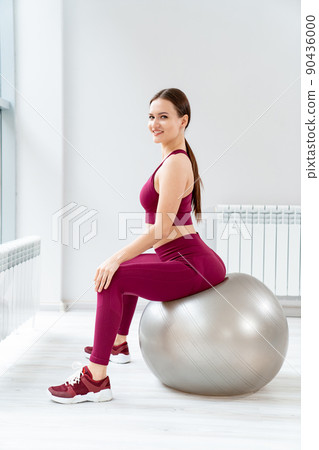 a beautiful and athletic girl in a burgundy tracksuit does gymnastics with ball a beautiful and athletic girl in a burgundy tracksuit does gymnastics with ball 90436000