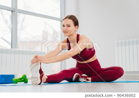 a girl in a tracksuit does exercises for muscle stretching and flexibility. 90436002