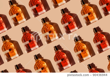 Pattern of different perfume bottles on a pastel beige background in the sunlight. Flat lay, top view. Luxury presentation mockup. Red, yellow and orange samples of aroma water 90436944