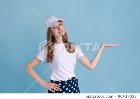 Cheerful young caucasian lady pointing at free space isolated on blue studio 90437038