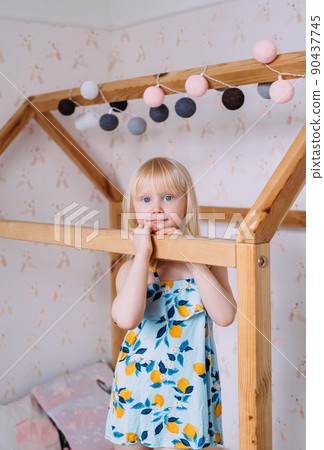 Little cute girl child blonde at home in her wooden bed house Little cute girl child blonde at home in her wooden bed house 90437745
