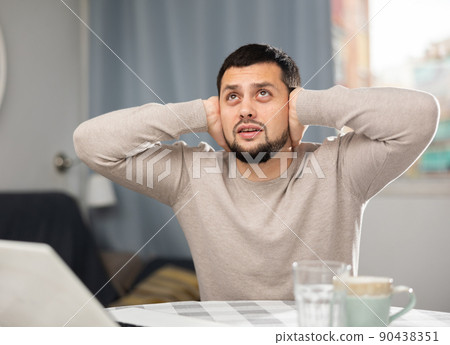 Man experiencing headache after working long hours on laptop Man experiencing headache after working long hours on laptop 90438351