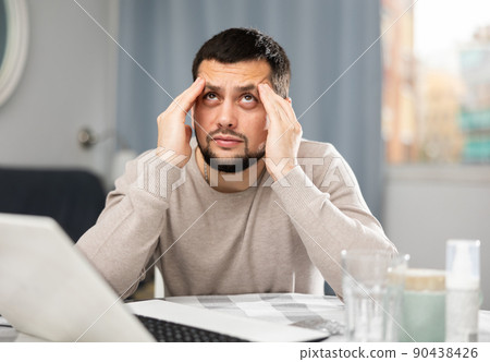 Man with pills in his hands is looking for diagnosis on the Internet using laptop 90438426