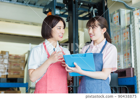 Female staff cheerfully working in a warehouse Female staff cheerfully working in a warehouse 90438875