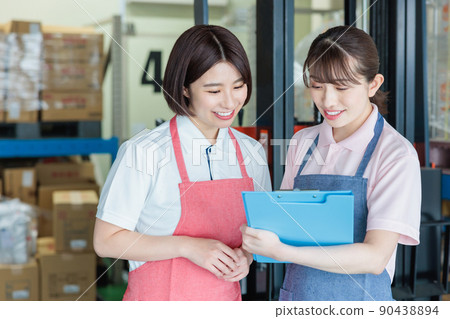 Female staff cheerfully working in a warehouse 90438894