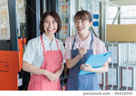Female staff cheerfully working in a warehouse Female staff cheerfully working in a warehouse 90438895