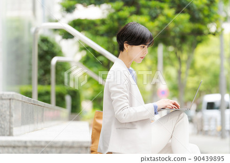 A woman operating a computer on the stairs A woman operating a computer on the stairs 90439895