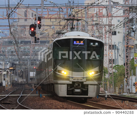 225 series rapid train running near Ashiya station at dusk 90440288