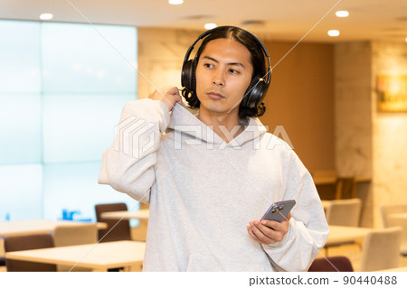 一個戴著耳機在智能手機上聽音樂的男人 90440488