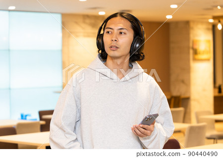 A man with headphones listening to music on his smartphone A man with headphones listening to music on his smartphone 90440490
