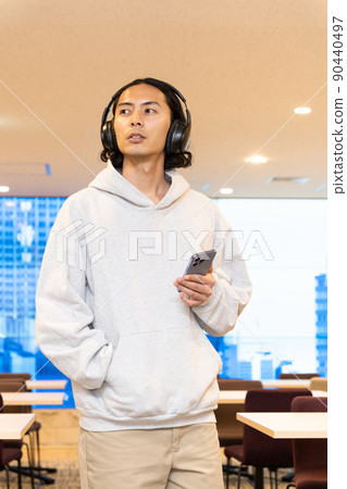 一個戴著耳機在智能手機上聽音樂的男人 一個戴著耳機在智能手機上聽音樂的男人 90440497