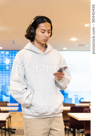 一個戴著耳機在智能手機上聽音樂的男人 一個戴著耳機在智能手機上聽音樂的男人 90440498