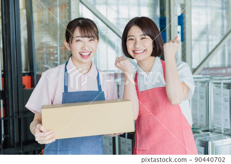 Female staff cheerfully working in a warehouse 90440702