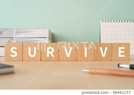 A desk with a block labeled "SURVIVE" 90442257