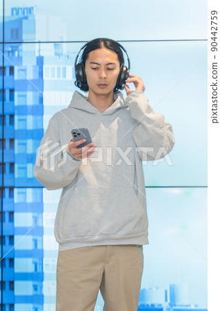A man in headphones standing in front of a huge monitor 90442759