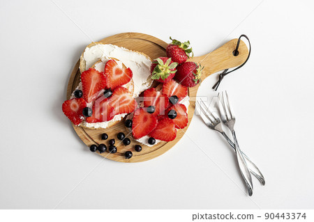 Toasts or bruschetta with strawberry and on cream cheese. Delicious breakfast or snack. Summer breakfast. 90443374