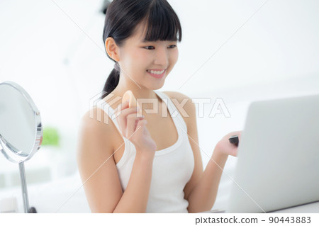Beauty of young asian woman with learning makeup with powder puff on cheek watching laptop. Beauty of young asian woman with learning makeup with powder puff on cheek watching laptop. 90443883