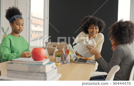 Classroom with diverse learners of happily African American students and teacher doing activities together. The teacher is teaching, guiding and talking to the children in diverse. 90444470