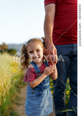 Little girl holding fathers hand,looking camera,smiling.Happy family, bonding, love. Summertime. Dad and daughter. Fathers day. 90444945