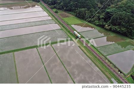 一列在水錶面上反射的稻田中運行的單列火車 90445235