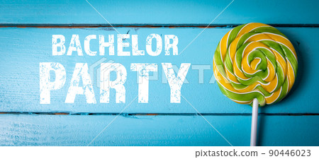 Bachelor Party. Yellow-green candy on a stick. Blue wood texture background 90446023