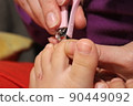 The master covers the customer's nails with varnish. Hands in gloves cares about a woman's foot nails. Pedicure, manicure beauty salon concept. Nail varnishing in red color. 90449092