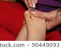 The master covers the customer's nails with varnish. Hands in gloves cares about a woman's foot nails. Pedicure, manicure beauty salon concept. Nail varnishing in red color. 90449093