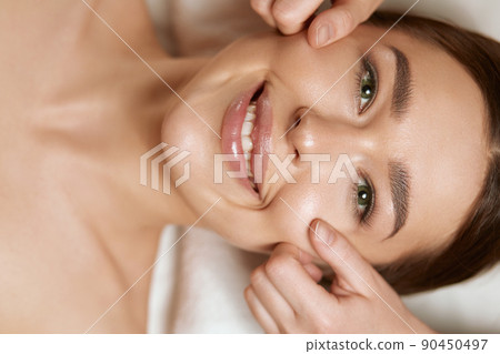 Beautiful of young woman getting spa massage. Face massage. Spa skin and body care. Facial beauty treatment. Cosmetology Beautiful of young woman getting spa massage. Face massage. Spa skin and body care. Facial beauty treatment. Cosmetology 90450497