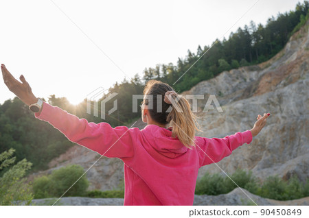 Young woman embracing life standing in nature with her arms spread widely Young woman embracing life standing in nature with her arms spread widely 90450849