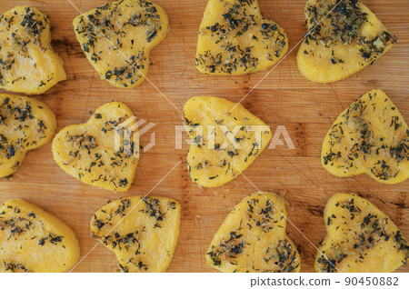 Polenta with herbs cut in heart shape placed on wooden board 90450882