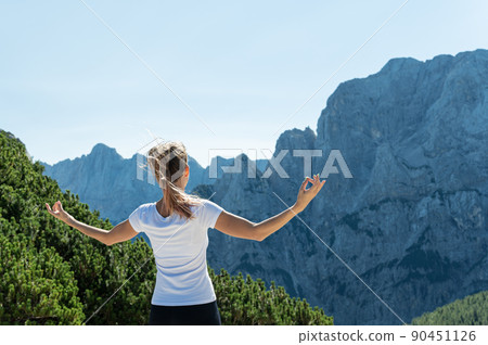 Young woman meditating with a view of mountains Young woman meditating with a view of mountains 90451126