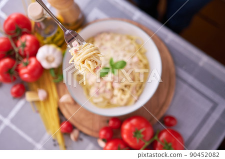 homemade pasta carbonara with fresh basil and parmesan in ceramic dish 90452082