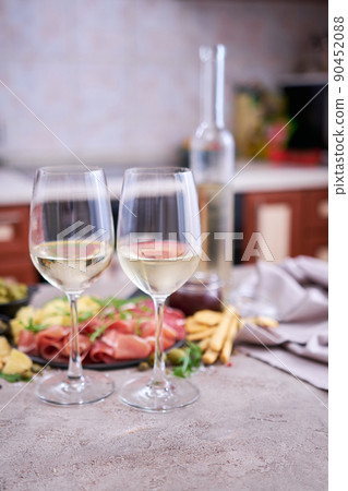 Two glasses of white wine with Italian antipasto meat platter on background 90452088