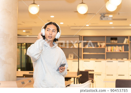 一個戴著耳機在智能手機上聽音樂的男人 一個戴著耳機在智能手機上聽音樂的男人 90453785