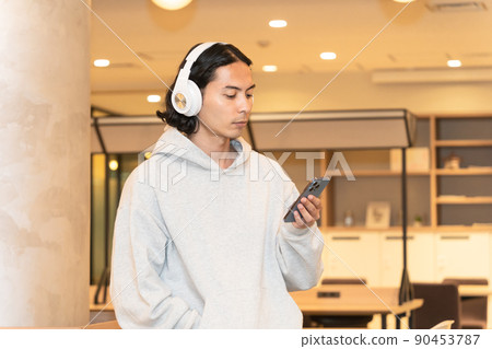 一個戴著耳機在智能手機上聽音樂的男人 一個戴著耳機在智能手機上聽音樂的男人 90453787