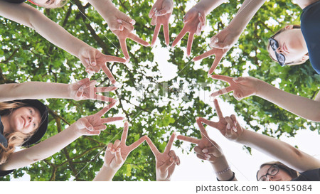 Girlfriends join fingers in a circle against the background of tree branches. Girlfriends join fingers in a circle against the background of tree branches. 90455084