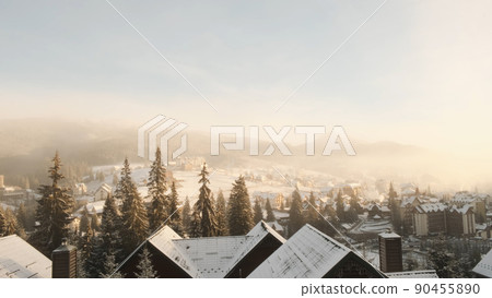 Top view of snow-capped rooftops of mountain hotel on winter morning haze. Ski hotels resort in Bukovel. Beautiful view of snow-covered ski village, houses, pine trees, forest, Carpathians Top view of snow-capped rooftops of mountain hotel on winter morning haze. Ski hotels resort in Bukovel. Beautiful view of snow-covered ski village, houses, pine trees, forest, Carpathians 90455890